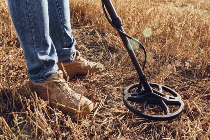 Man with metal detector equipment searching for metal goods in the field