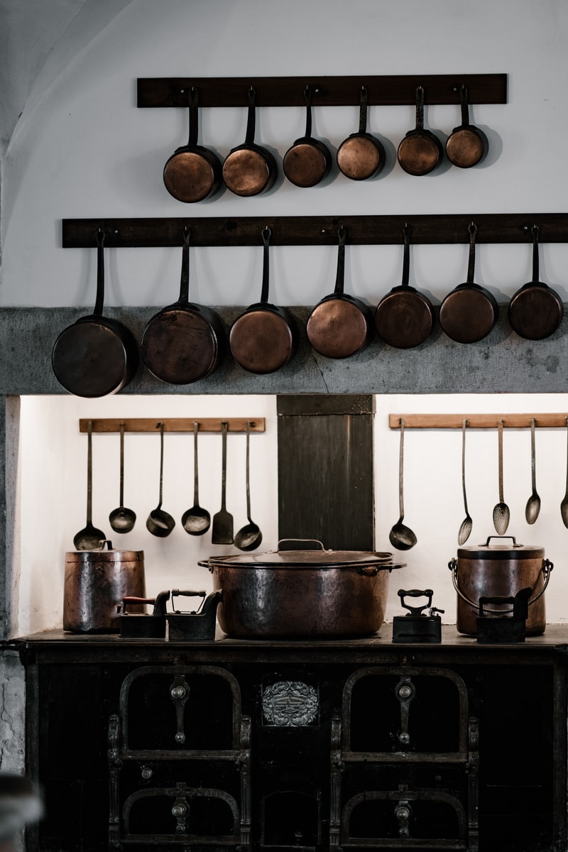 assorted cooking pots and pans hangs over black cast iron stove